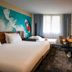 Novotel Antibes Sophia Antipolis guest room with twin beds, desk, wall TV and large window in Valbonne