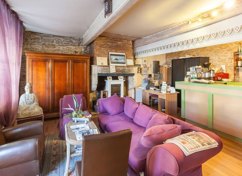 Logis Auberge La Cremaillere in Villandraut lounge with purple sofa, bar counter and stone fireplace