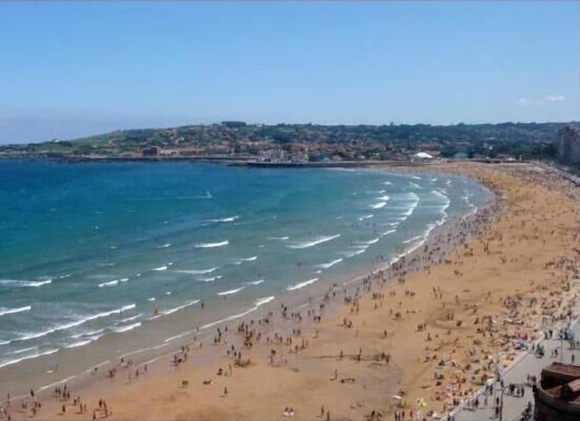 Hotel Asturias in Gijón overlooking a wide sandy beach and sweeping bay with crowds along the shore