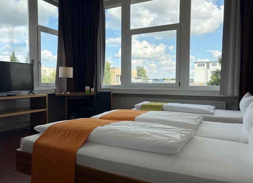 AMH Airport-Messe-Hotel Stuttgart guest room with twin beds and large city-view windows in Filderstadt