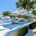 Seven Secrets by Hanging Gardens, Senggigi: oceanfront pool deck with loungers, umbrellas and palm trees