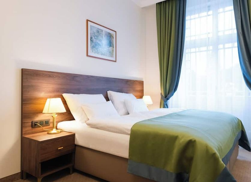 Spa Hotel Villa Smetana in Carlsbad bedroom with double bed, bedside lamps and green curtains