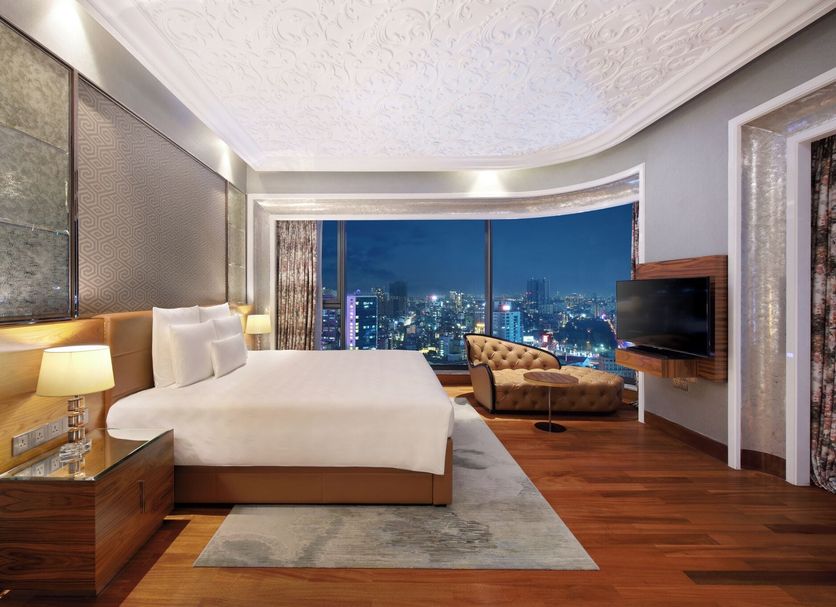 The Reverie Saigon Residential Suites bedroom with city skyline view in Ho Chi Minh City