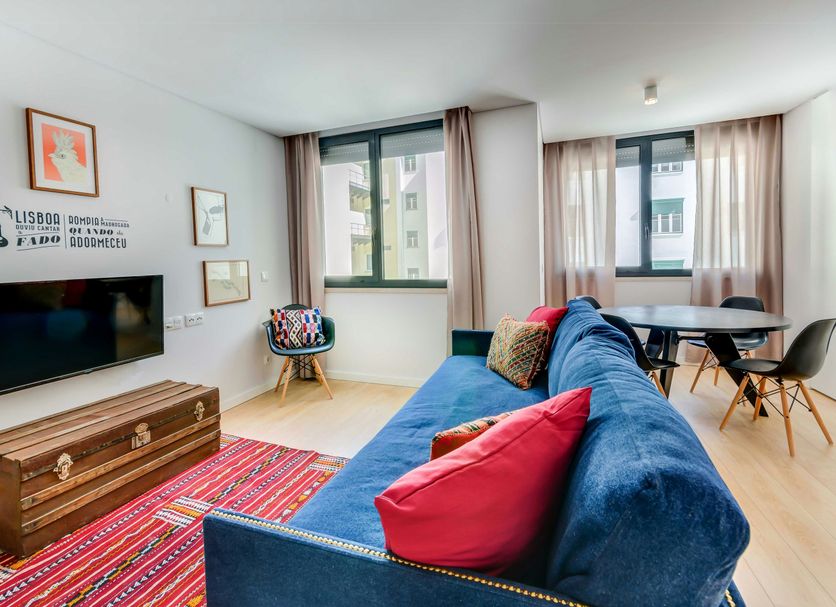 Lsa Liberdade by Numa in Lisbon living room with blue sofa, TV, dining table and large windows