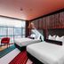 Naumi Hotel Wellington room with two beds, colorful striped rug, and large window view in Wellington