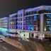 TIME Grand Plaza Hotel in Dubai at night, lit with colorful facade lights along a curved street