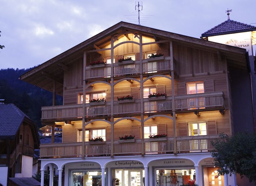 Christophorus Mountain Residence in San Vigilio di Marebbe, lit alpine hotel facade with balconies at dusk