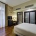 Sercotel Puerta de la Catedral in Salamanca, stone-accent room with green chair, bed and balcony doors