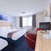 Travelodge Hull South Cave guest room in Brough with two beds, desk, TV and window light