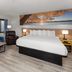 Days Inn by Wyndham Mason City guest room with king bed, sofa, armchair and wall art