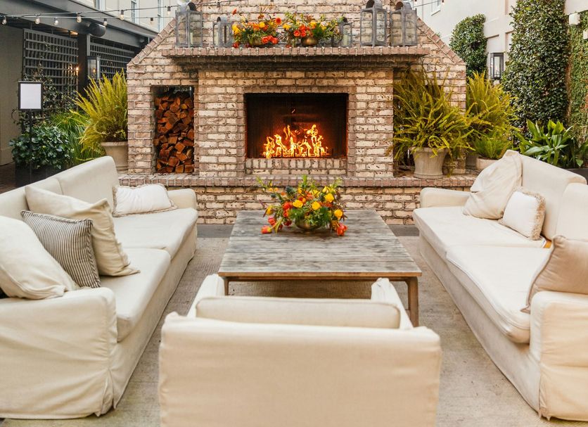 Emeline Charleston courtyard with brick fireplace, lounge seating and potted flowers