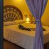 Villa dei Papiri in Siracusa bedroom with wrought-iron headboard and purple curtains by a glass door
