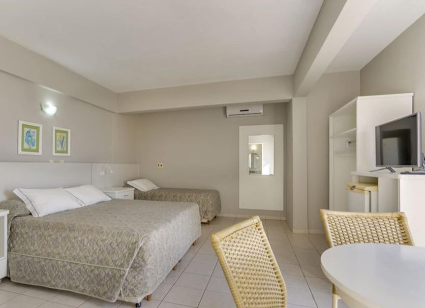Canasvieiras Hotel in Florianopolis guest room with two beds, small dining table, and TV