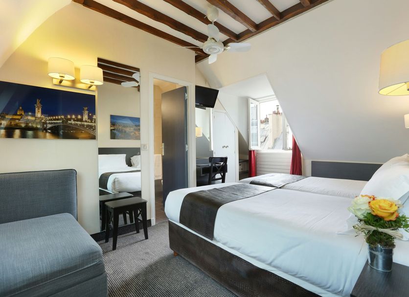 Hotel du College de France room in Paris with twin beds, exposed beams and city view artwork