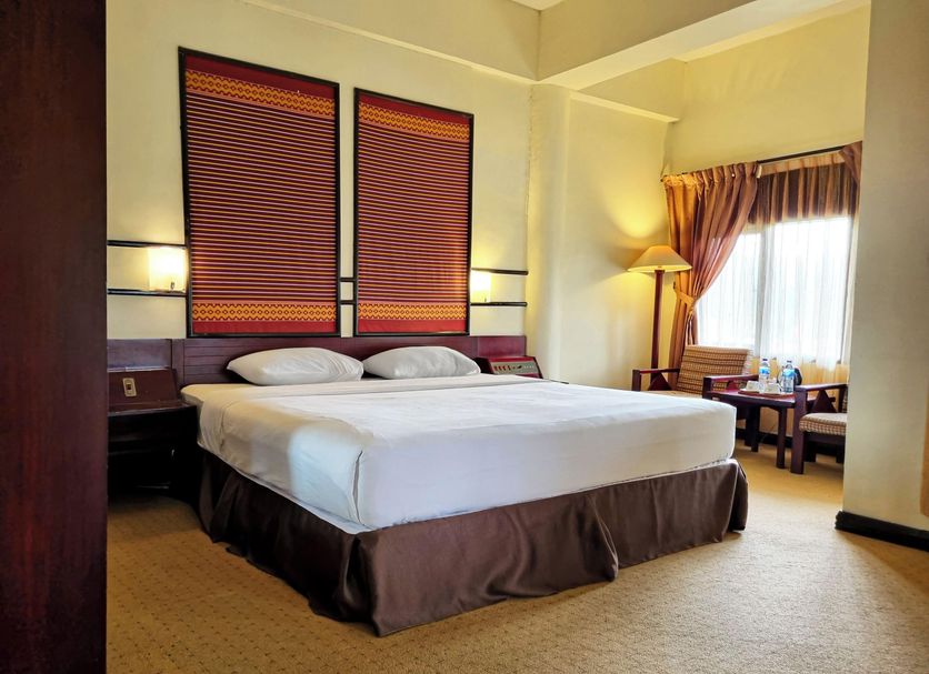Hotel Sibayak International room in Berastagi with king bed, tall windows and seating area