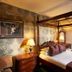 Loch Kinord Hotel in Aboyne bedroom with four-poster bed, plaid bedding, bedside lamp and patterned curtains