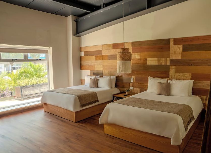 Mayan Monkey Cancun | Social Hotel in Cancún guest room with two beds and wood-paneled accent wall