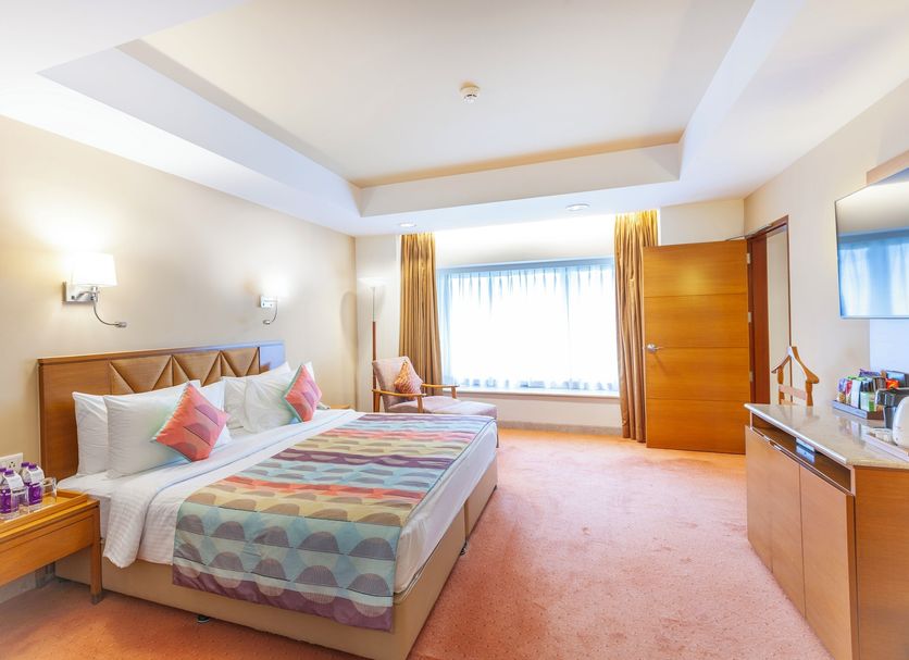 Fortune Park Lake City, Thane guest room with king bed, large window, and dresser