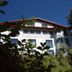 Hotel Planaiblick in Schladming, white alpine hotel viewed through greenery under a clear blue sky