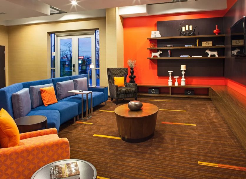 Courtyard by Marriott London lounge with blue sectional seating, orange chairs, coffee table and wall shelves