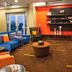 Courtyard by Marriott London lounge with blue sectional seating, orange chairs, coffee table and wall shelves