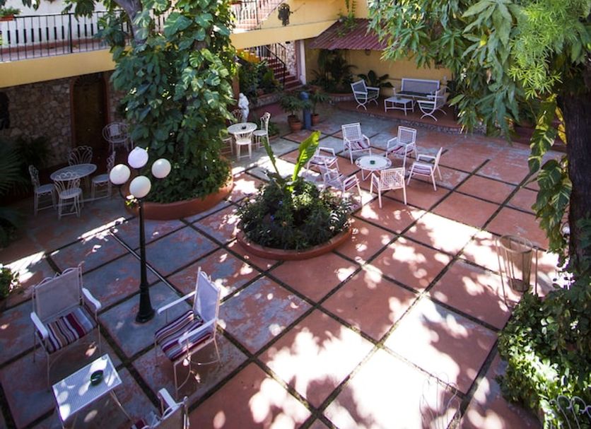 Ideal Villa Hotel in Port Au Prince courtyard with tables, chairs, umbrellas and lush tree canopy