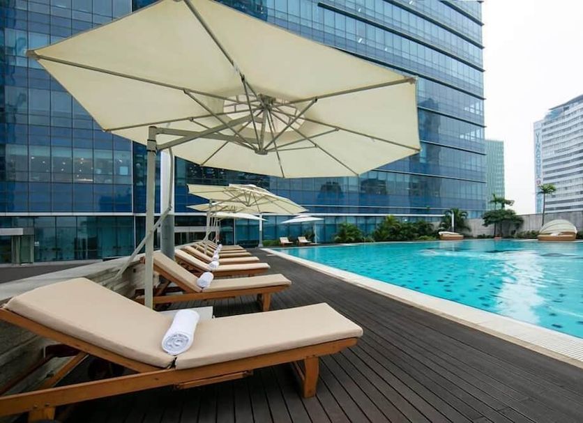 Calidas Landmark72 Royal Residence Hanoi pool deck with loungers, umbrellas and city high-rise backdrop