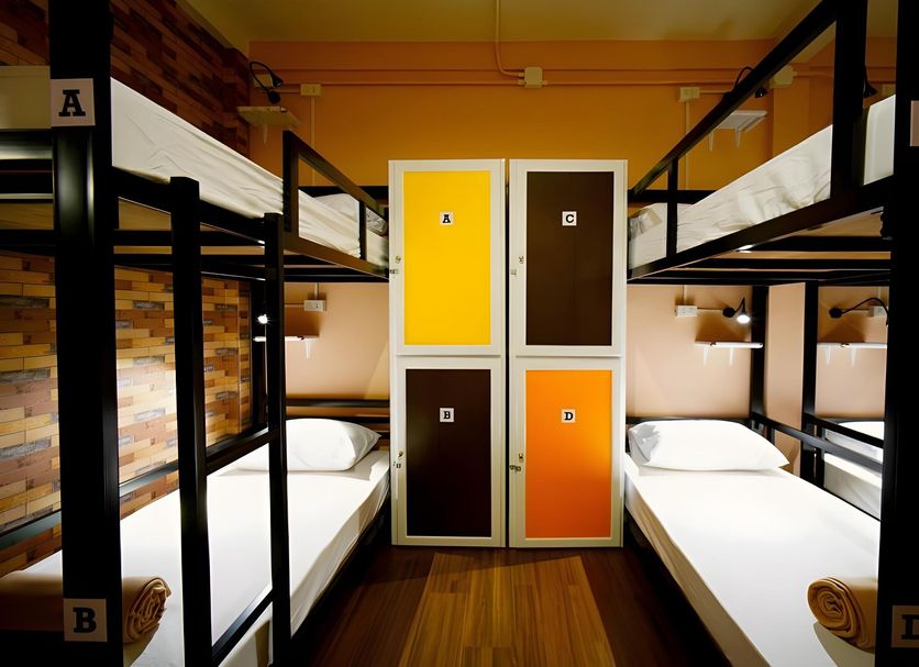 Urban Hostel Bangkok dorm room with black bunk beds, white linens, and colorful locker doors