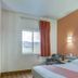 Motel 6 Roseburg room with queen bed, window view, chair, and wall sconces in Roseburg