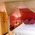 Glenskirlie Castle Hotel in Glasgow bedroom with canopy bed, red patterned walls and bedside lamps
