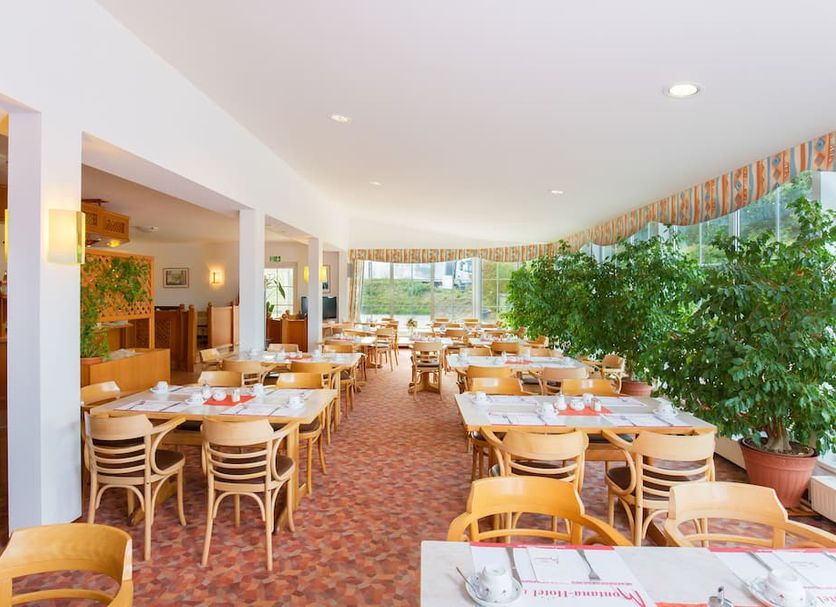 Hotel Montana Lauenau in Lauenau restaurant with wicker chairs, set tables, and large windows
