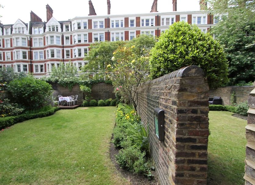 Ridgemount Hotel London garden with lawn, brick wall, and row of townhouses