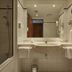 H4 Hotel Kassel bathroom in Kassel with bathtub, shower, sink, and wall-mounted hairdryer