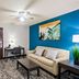 Best Western Fort Wayne Inn & Suites North guest room with sofa, desk, TV and blue accent wall