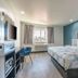 Studio 6 Suites Perris room with king bed, desk, window, and teal accent wall