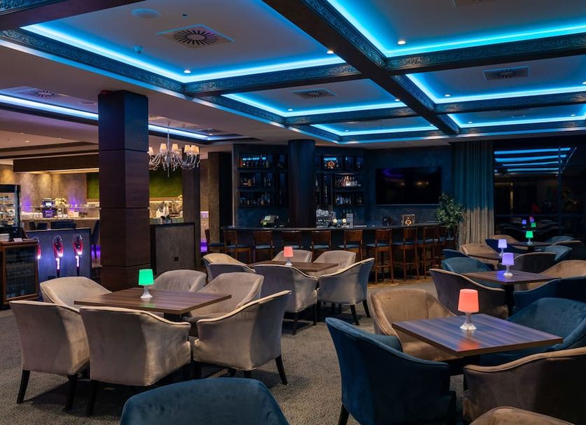 Crowne Plaza Vilnius in Vilnius lounge bar with blue-lit ceiling, tables and upholstered chairs
