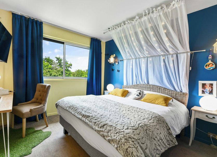 Logis Hôtel & Restaurant Ludik Bergerac guest room with canopy bed, desk, TV and garden-view window