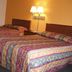 Executive Inn Rocky Top room with two patterned beds and a lit bedside lamp