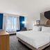 Spark by Hilton Merrillville guest room with king bed, large window, chair and TV