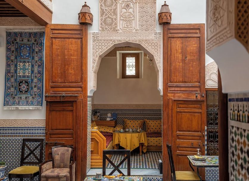 Dar D'or Fes in Fez: ornate Moroccan archway with carved wood doors and patterned lounge seating