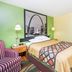 Super 8 by Wyndham Jacksonville guest room with bed, striped armchair, and black-and-white wall art
