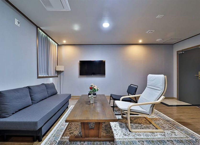 Hotel Noah Busan lounge with gray sofa, coffee table, TV, and white lounge chair