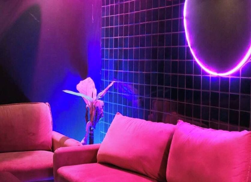 Thezen Hotel Yasothon lounge with pink sofas, neon wall ring light and dark tiled wall