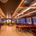 Hotel Grand Palace, Chennai dining room with large windows, warm ceiling lights and red chairs