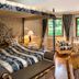 Hotel Bareiss in Baiersbronn guest room with canopy bed, armchairs, and large windows overlooking greenery