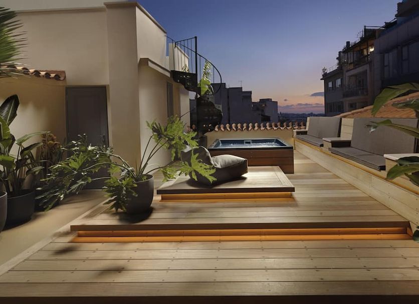 Monument Hotel Athens rooftop terrace with lounge seating, potted plants and a sunset city view