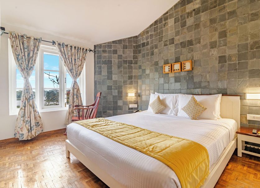 Sterling Kodai Lake in Kodaikanal bedroom with lake-view windows, patterned curtains and yellow bed runner