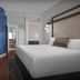 Hotel Indigo Jacksonville-Deerwood Park guest room with king bed, TV, desk and blue privacy curtain in Jacksonville