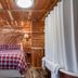 Log Cabin Inn in Eureka Springs cabin-style guest room with plaid bed, wood walls, and ceiling light