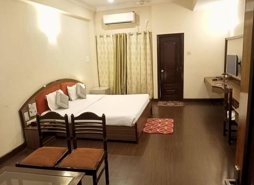 The Citi Inn Jamshedpur guest room with bed, desk, TV, chairs and air conditioner